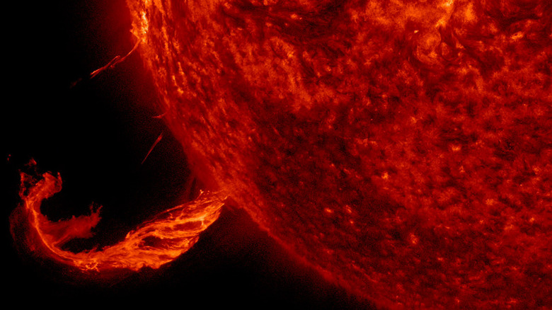 A solar flare ejects from the Sun's fiery red surface.