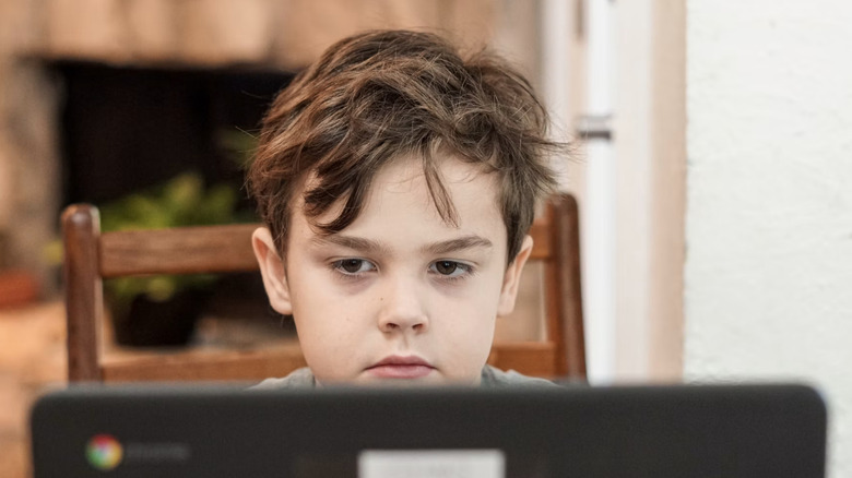 A kid blankly looking at a screen.