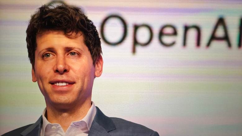 A man in front of the OpenAI logo.