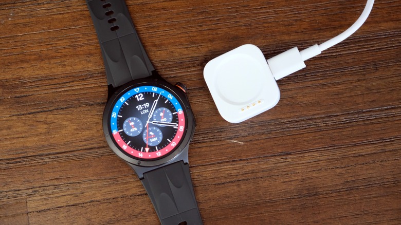 Oppo Watch X3 on a table next to its charging puck.