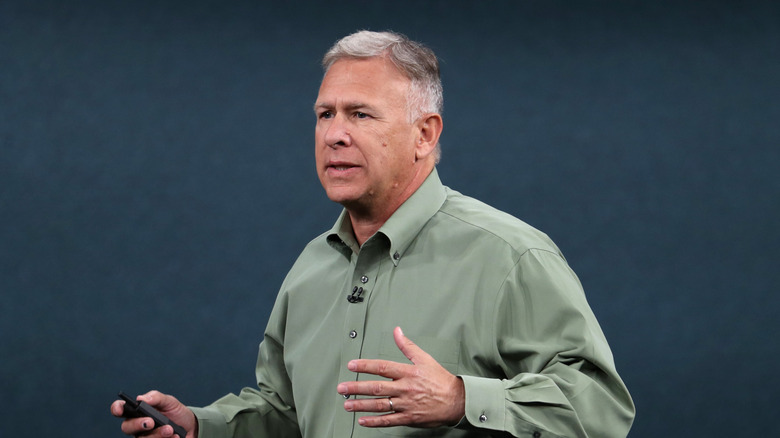 A man in a green shirt holds a presentation remote.