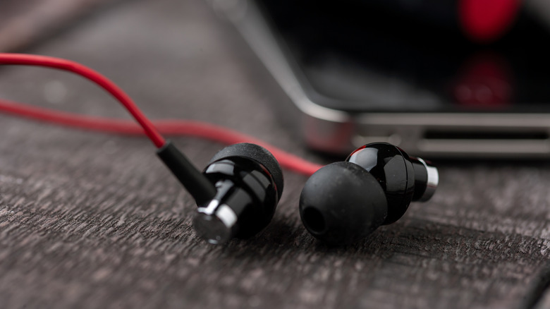 Close-up shot of wired earbuds next to a smartphone.