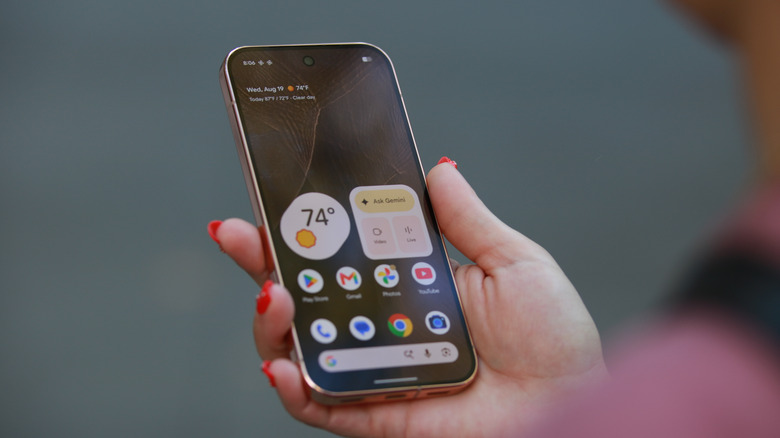 The Pixel 11 Pro held up in mid-air with its home screen facing up.