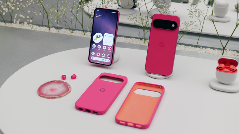 The Google Pixel 11 in its hot pink Hibiscus colorway, sitting among accessories like cases and ear buds.