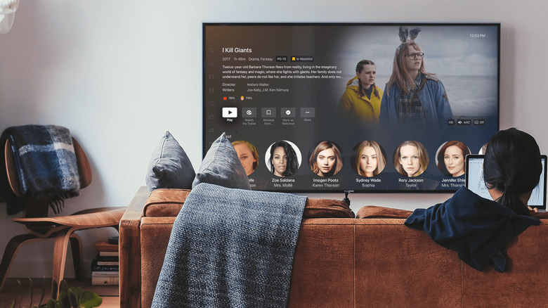 Person watches TV on couch with Plex interface onscreen