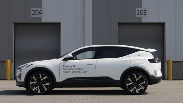 Photo showing a white Polestar 3 electric SUV in front of two gray warehouse garage doors.