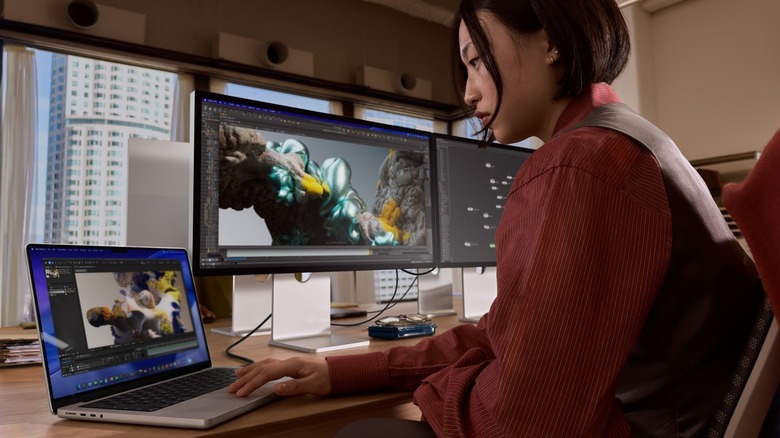 Woman using an Apple MacBook Pro with Apple Studio Display XDR 5K display.