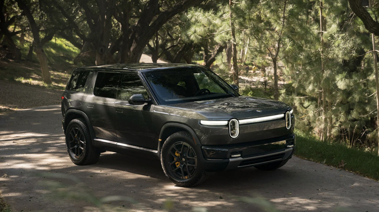 A Rivian vehicle in the background of the forest.