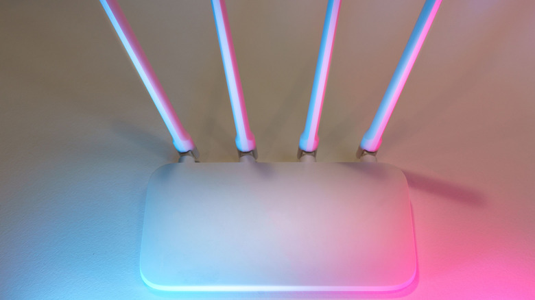 White router on white table with pink and blue lighting coming from the right-hand lower corner
