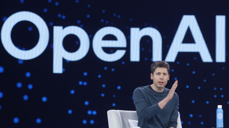 Sam Altman in front of the OpenAI company logo.