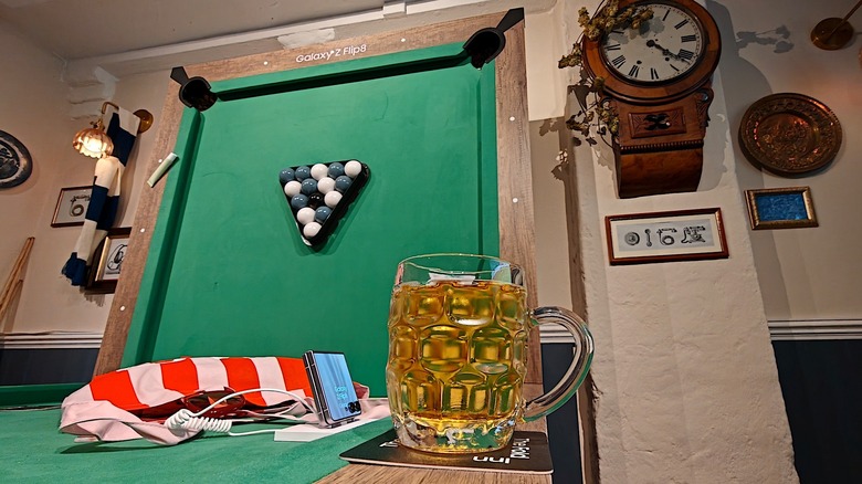 A 'folded' pool table with a Galaxy Z Flip 9 and a pint of beer.