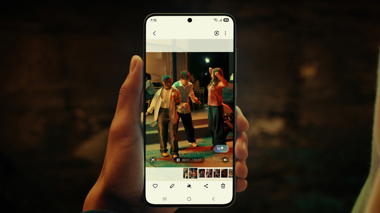 A hand holding up the Samsung Galaxy S25 FE taking a photo of three young adults in the street.