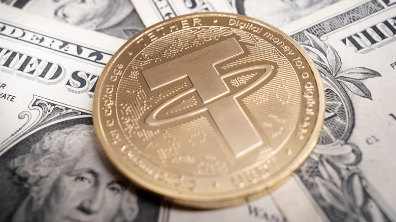 Gold coin depicting a Tether cryptocurrency logo on top of US banknotes.