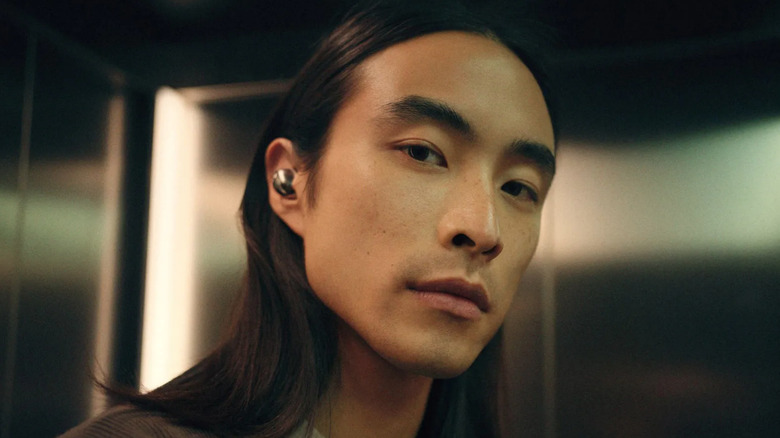 A handsome man wears an earbud.