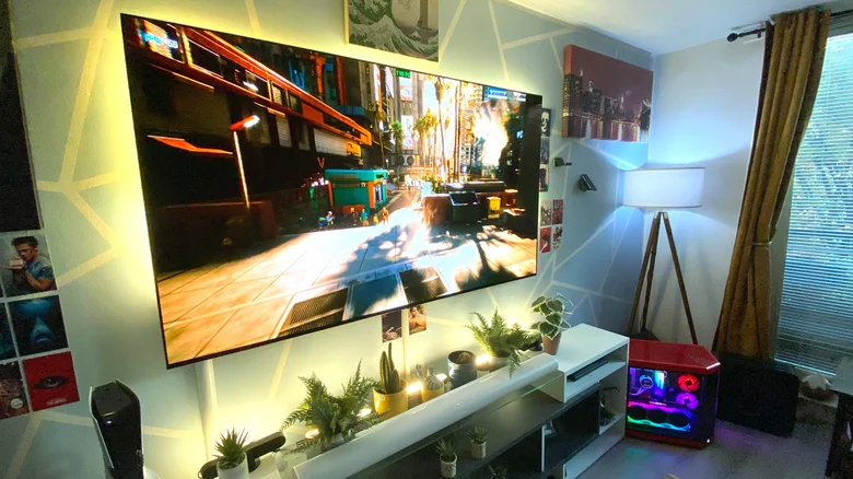 Cyberpunk 2077 on a large OLED TV in a living room, with a gaming PC in view.