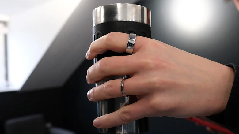 The Oura Ring 4 on a hand holding a water bottle