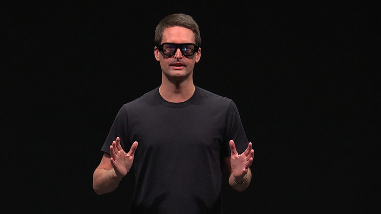 Snap CEO Evan Spiegel on a stage in front of a black background, wearing Specs on his face.