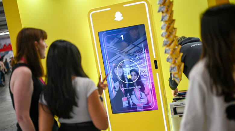 Two people posing for a Snapchat photo at a photobooth.