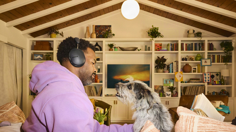 A person wearing the Sonos Ace Ultra headphones and a cute doggo.