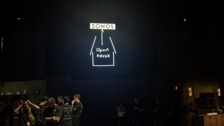 The Sonos Open House logo on a dark screen at a dimly lit event space.