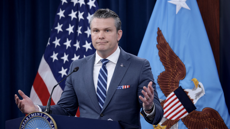 Defense Secretary Pete Hegseth shrugging at a podium