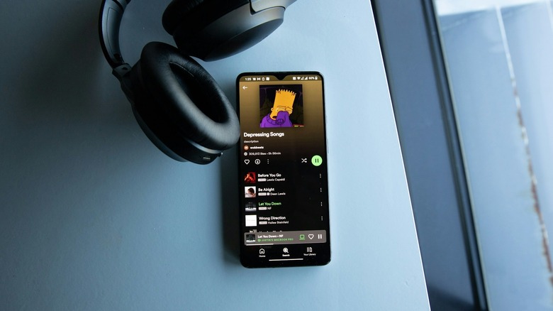 Headphones next to a phone showing a Spotify playlist called 