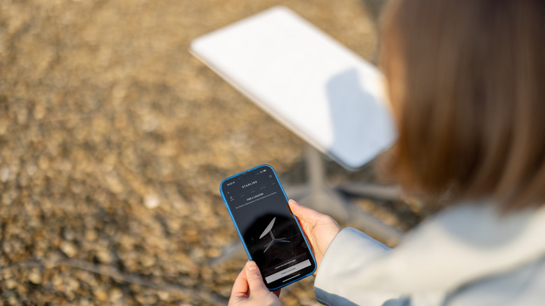 A person sets up a Starlink dish outside.