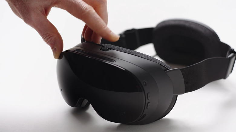 Closeup of the Steam Frame VR headset, with a person's hand touching it.