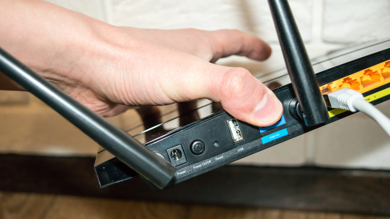 Hand holding a router, showing the various ports on the back.