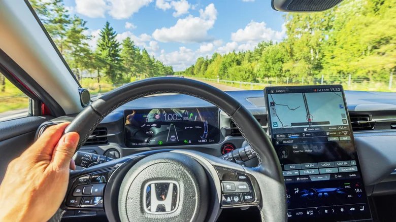 A close-up of the cabin of a Honda from the driver's point of view, including a digital cockpit