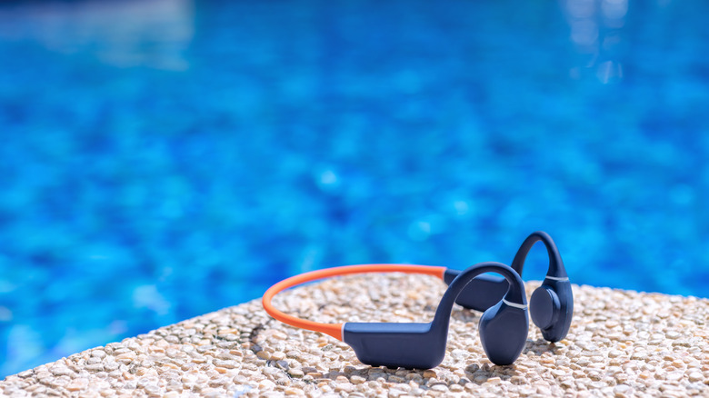 Bone conduction headphones on the ground next to a pool