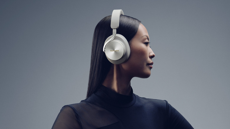 Photo of a woman with dark hair and clothing shown in profile wearing silver Technics over-ear headphones.