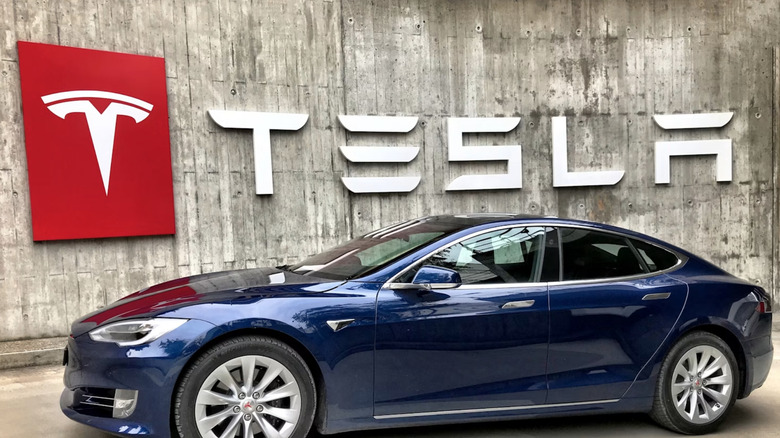 A Tesla car in front of a Tesla sign in a Tesla showroom.