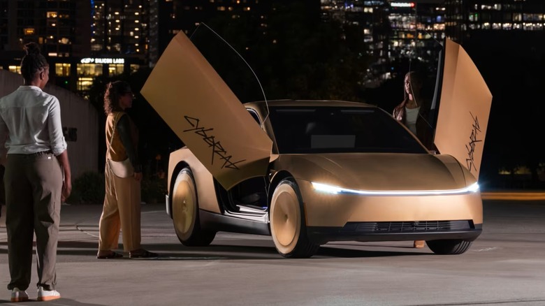 People entering a gold vehicle with gull-wing doors at night.