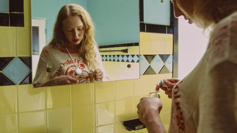 A woman brushing her teeth while wearing a white, circular Friend pendant.