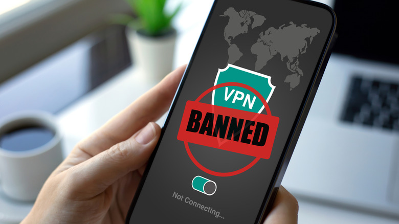 A person attempting to use a VPN on their phone with a red BANNED symbol across the screen.