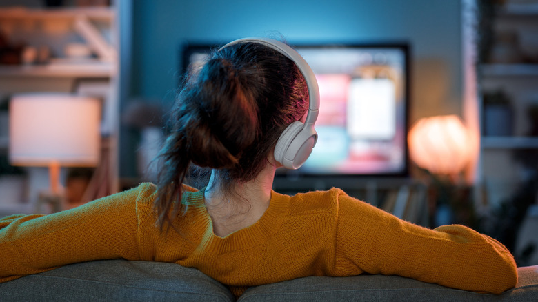 Person watching TV while wearing headphones and sitting on couch
