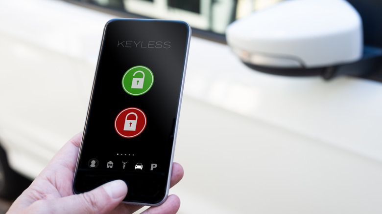 A hand holding a phone up to a car showing keyless entry to lock and unlock.