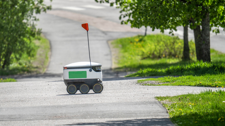 A delivery robot with a flag driving on a road