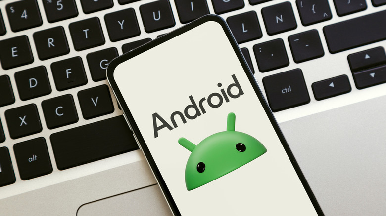 Android logo on a phone's display placed over a keyboard.