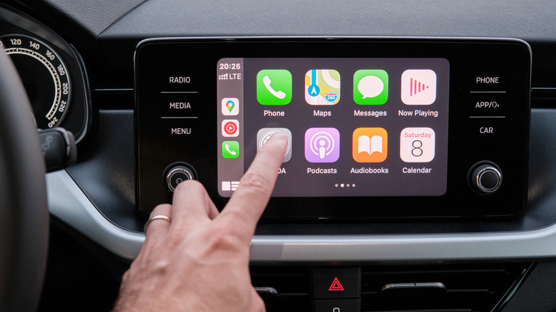 Person's hand touching a CarPlay display.