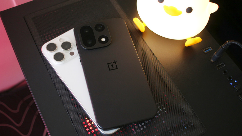 A OnePlus 15 sitting on top of an iPhone 15 Pro Max