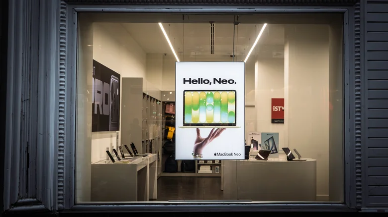 A MacBook Neo banner luring shoppers into a tech shop.