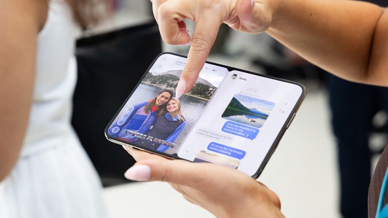 Finger pointing to an iPhone Duo that's showing Photos and Messages simultaneously.