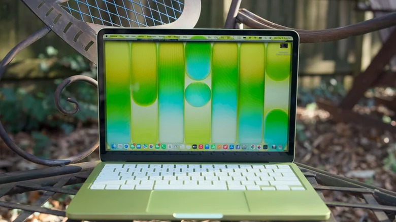 A green MacBook Neo open on a bench.