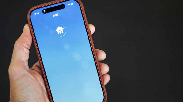 Closeup of a phone with the Nest app stuck on a loading screen