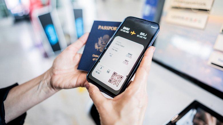 Hands holding a passport and digital airline ticket on a phone.