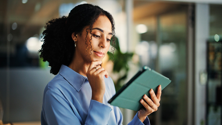 Woman holding an iPad with a green case.