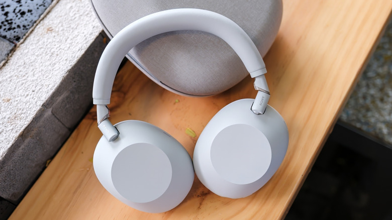 White Sony headphones with ANC on a table next to their case.