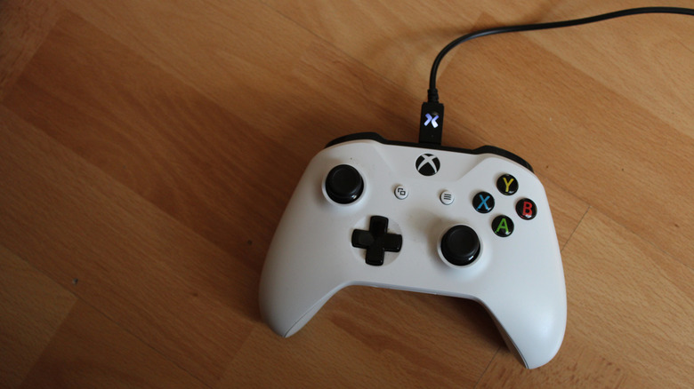 A white Xbox One-era controller, connected by USB cable.